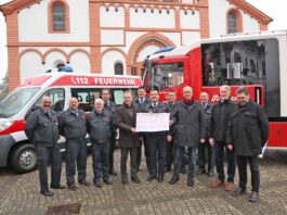 Gemeinsam überreichen Pastor Frank Werner, Hans Seul und Kurt Heuser (v.r.n.l.) den symbolischen Spendenscheck an Stadtwehrleiter Andreas Braun, Vertreter der Löschgruppen aus dem Stadtgebiet und Bürgermeister Andreas Geron. Foto: Stadtverwaltung Sinzig/Melanie Walkenbach